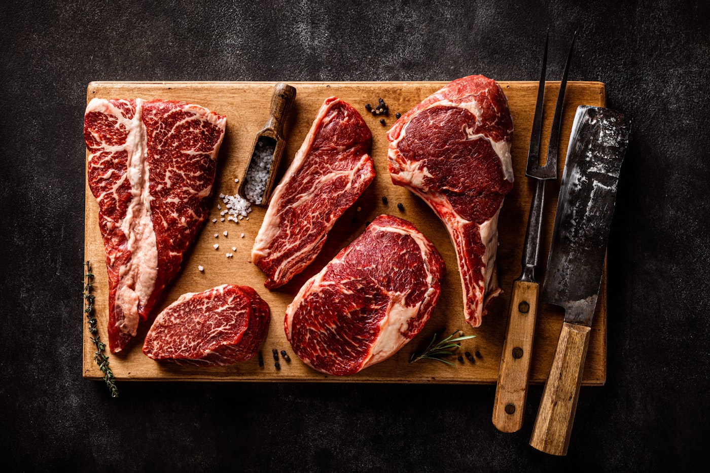 Fresh raw beef cuts arranged on a wooden cutting board with a knife